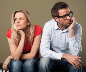 woman and man with chins in their hands looking away from one another as they contemplate how to rebuild trust after infidelity