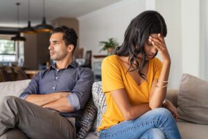 Couple in an argument sitting on the couch in an article by Stefanie Kuhn on how to stop fighting in a relationship.