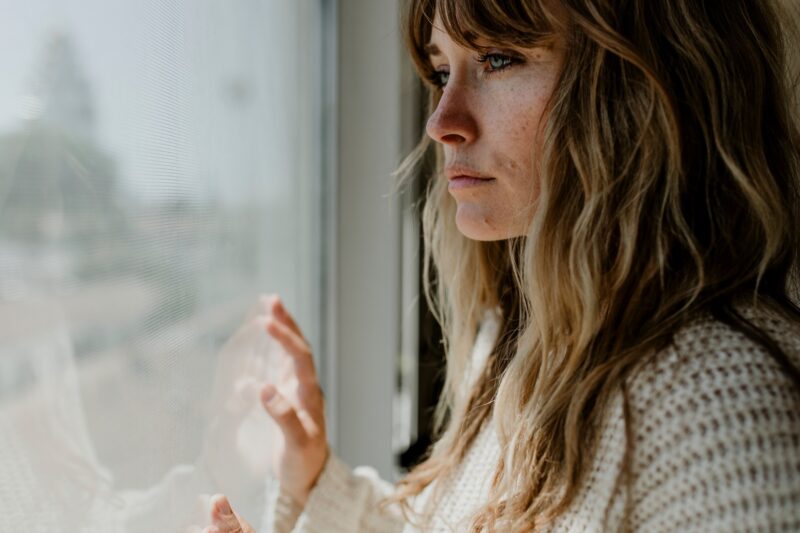 Woman looking out the window in an article by therapist Stefanie Kuhn on how to stop cheating.