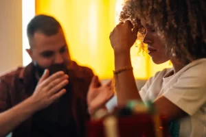 Young woman feeling sad while boyfriend trying to explain himself