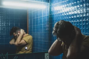 Close up of one sad depressed man looking himself in the mirror of the bathroom reflexing