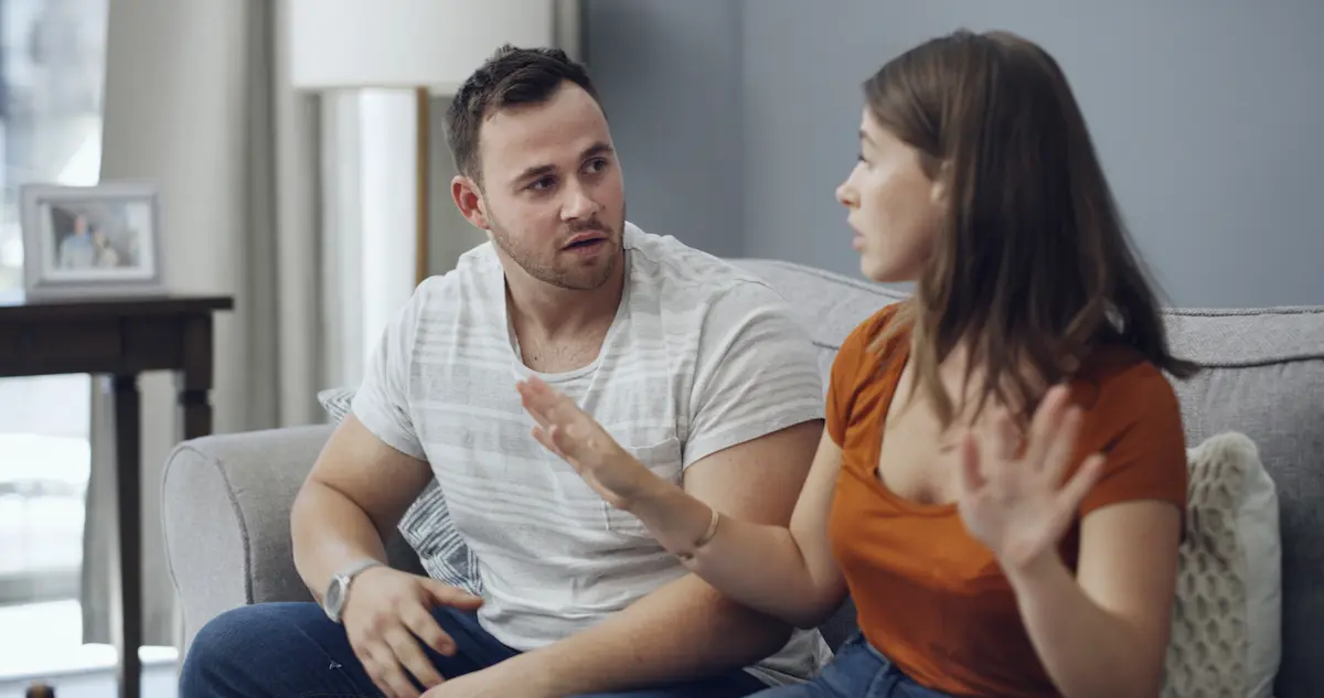 Couple having tense conversation on couch illustrating challenges addressed in a marriage intensive