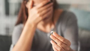 Woman holding a wedding ring with her face covered symbolizing divorce separation marital grief and emotional loss