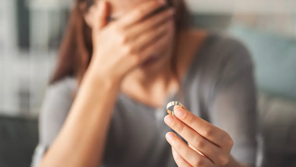 Therapy that works with stefanie kuhn | therapyworks texas Woman holding a wedding ring with her face covered symbolizing divorce separation marital grief and emotional loss